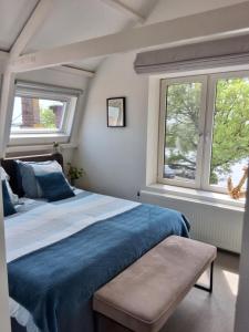 a bedroom with a blue bed and two windows at Appartement Havenzicht in Enkhuizen