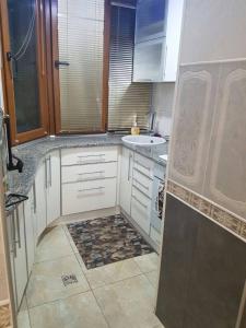 cocina con armarios blancos y suelo de baldosa en Квартира возле парка Софиевка en Umanʼ