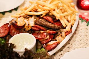 a plate of food with french fries and sausage at Pousada suite avencal in Urubici