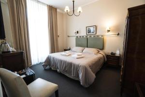um quarto de hotel com uma cama e uma cadeira em Hotel Colonial Salta em Salta