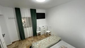 a bedroom with a bed and two chairs and a dresser at Vila Theo in Mangalia