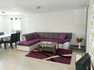 a living room with a purple couch and a table at 3 bedrooms apartement with furnished garden and wifi at Rakovica in Rakovica