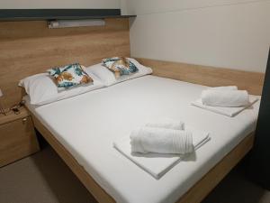 a bed with white sheets and pillows on it at Mobile Homes Pirovac with 2 shared Pools in Pirovac