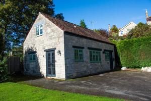 - un petit bâtiment en pierre avec des fenêtres vertes sur une cour dans l'établissement The Snug, Beautiful Country Retreat, à Priston