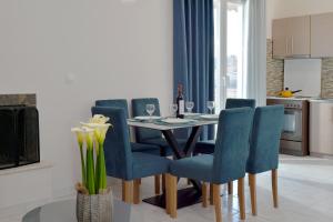 a dining room with a table and blue chairs at Stork Apartments in Vivari
