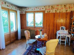 Una sala de estar con mesa y sillas y ventanas. en La Maison des Praz, en Saint-Gervais-les-Bains