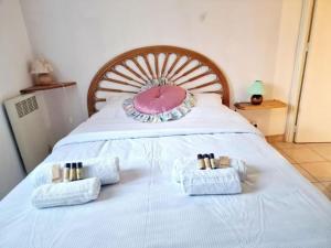 un letto con cuscino rosa e due asciugamani sopra di Les Calanques YourHostHelper a Fréjus