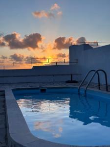 a swimming pool with a sunset in the background at Casa Condessa - Create memories in Azenhas do Mar +44 photos