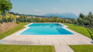 una piscina en medio de un césped con árboles en La Terrazza sul Lago - Italian Homing, en Polpenazze del Garda
