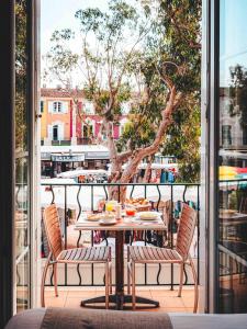 uma mesa e cadeiras numa varanda com uma árvore em Le Suffren Hôtel em Grimaud