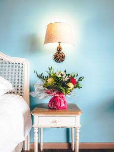 un vase de fleurs sur une table à côté d'une lampe dans l'établissement Le Suffren Hôtel, à Grimaud