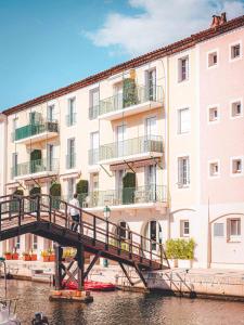 a man walking across a bridge over a river in front of a building at Le Suffren Hôtel in Grimaud