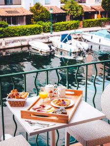 - une table avec un plateau de nourriture et de boissons sur un balcon dans l'établissement Le Suffren Hôtel, à Grimaud