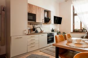 uma cozinha com armários brancos e uma mesa de madeira em Apartament Złota Perła em Czarny Dunajec