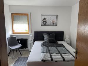 een slaapkamer met een bed, een stoel en een raam bij Ferienwohnung Alpenblick in Bruckmühl