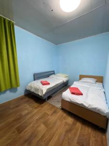 2 Betten in einem Zimmer mit grünem Vorhang in der Unterkunft Mini hotel in Almaty