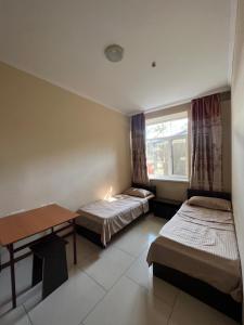 Zimmer mit 2 Betten, einem Tisch und einem Fenster in der Unterkunft Mini hotel in Almaty