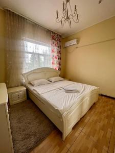 a bedroom with a bed and a window and a chandelier at Mini hotel in Almaty