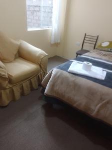 a bedroom with a bed and a couch and a chair at killa andina inn in Puno