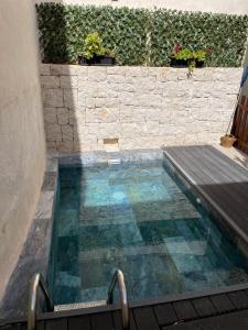 una piscina con terraza de madera junto a una pared de ladrillo en Casa Rural Sarsalet, en Chella