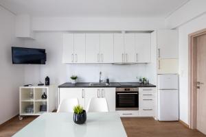 a kitchen with white cabinets and a table and chairs at Boutique Studios near Airport in Pallini