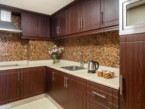 a kitchen with wooden cabinets and a sink and flowers at Dream Inn Apartments - Luxury 2BR in Marjan Island Close to Beach in Ras al Khaimah