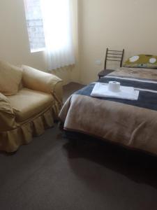 a bedroom with a bed and a couch and a window at killa andina inn in Puno