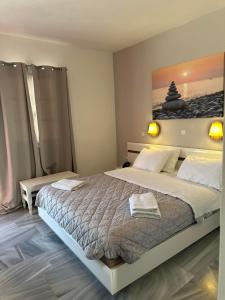 アギオス・ソスティスにあるAkrogiali Hotelの大きなベッド付きのベッドルーム1室、壁に絵画が飾られています。