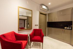een woonkamer met 2 rode stoelen en een spiegel bij premium sea porto marina suite in El Alamein