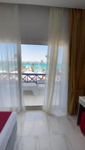 een slaapkamer met een groot raam met uitzicht op de oceaan bij premium sea porto marina suite in El Alamein