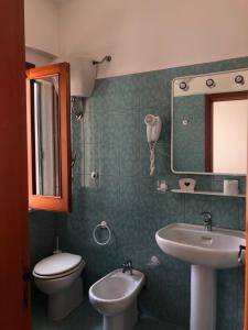 a bathroom with a sink and a toilet and a mirror at Hotel Ariston in Ustica
