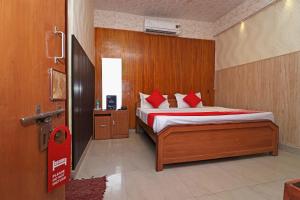 OYO 13234 Hotel Mahak في Bijnaur: غرفة نوم بسرير ومخدات حمراء