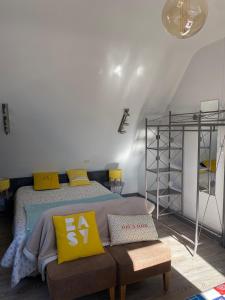 a bedroom with a bed with yellow pillows and a bench at Studio perros guirec village préféré des Français in Perros-Guirec