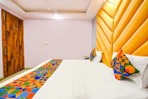 ein Schlafzimmer mit einem weißen Bett mit einer farbenfrohen Tagesdecke in der Unterkunft FabHotel Iris Lite in Neu-Delhi