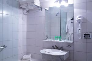 Baño blanco con lavabo y espejo en Hotel Presidente Buenos Aires en Buenos Aires