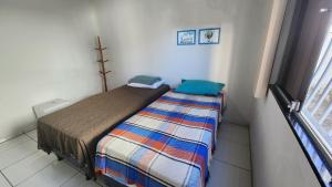 een klein bed in een kleine kamer met een sprei bij Casa 1km praia in São Mateus