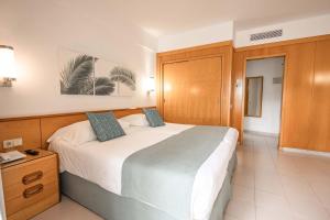 a bedroom with a large bed and a wooden cabinet at Servatur Don Miguel - Adults Only in Playa del Ingles