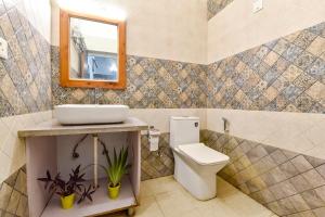 uma casa de banho com um WC, um espelho e um lavatório. em FabHotel KK Residency em Mājra