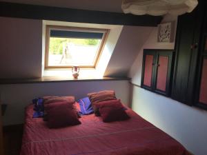 a bedroom with a bed with red sheets and a window at Le cottage normand in Saint-James