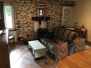 a living room with a couch and a stone wall at Le cottage normand in Saint-James