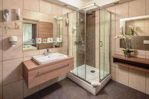 ein Bad mit einer Glasdusche und einem Waschbecken in der Unterkunft Vitta Hotel Superior in Budapest