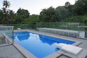 a swimming pool with blue water and a fence at Ranghavi sands Apartment with Pool - near beach and Dabolim Airport in Bogmolo