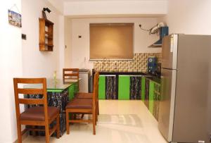 a kitchen with a refrigerator and a table and chairs at Ranghavi sands Apartment with Pool - near beach and Dabolim Airport in Bogmolo