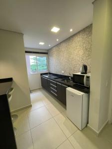 a kitchen with a sink and a microwave at Residencial Dona Clara in Pontal do Paraná