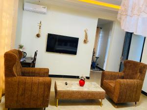 uma sala de estar com 2 cadeiras e uma televisão de ecrã plano em MLIMWA HILL PALACE em Dodoma