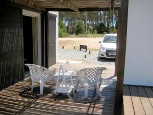 a porch with chairs and a table and a car at Casa de Familia Jiro in Punta Del Diablo