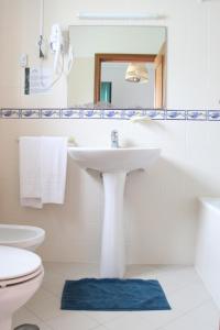 a white bathroom with a sink and a toilet at Casas do Monte in Palmela