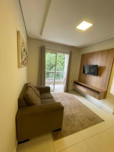 ein Wohnzimmer mit einem Sofa und einem TV in der Unterkunft Residencial Dona Clara in Pontal do Paraná