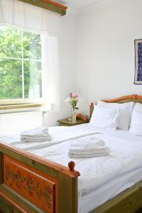 um quarto com uma cama com lençóis brancos e uma janela em Székely Kúria em Miskolctapolca