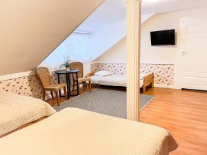 オルシュティネクにあるWiatraki Nature Resortのベッド2台、テーブル、テレビが備わる客室です。